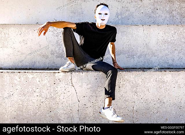 Man with white color face mask sitting on wall