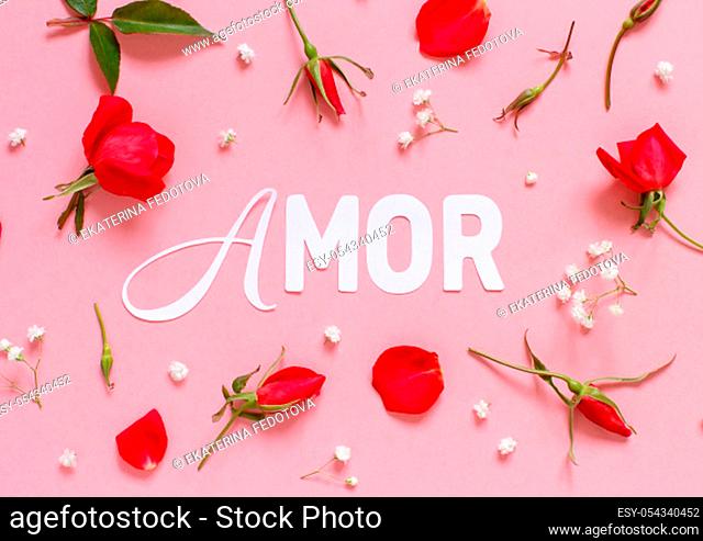 Pink roses and text AMOR on a light pink background top view