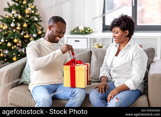 happy african couple with christmas gift at home
