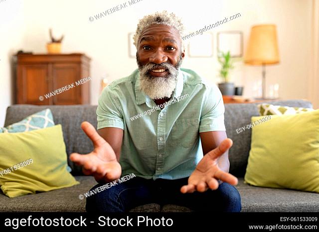 African american senior man sitting on sofa making video call smiling and gesture