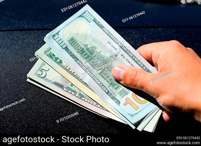 A man hands over money in a car. A wad of dollars in his hand