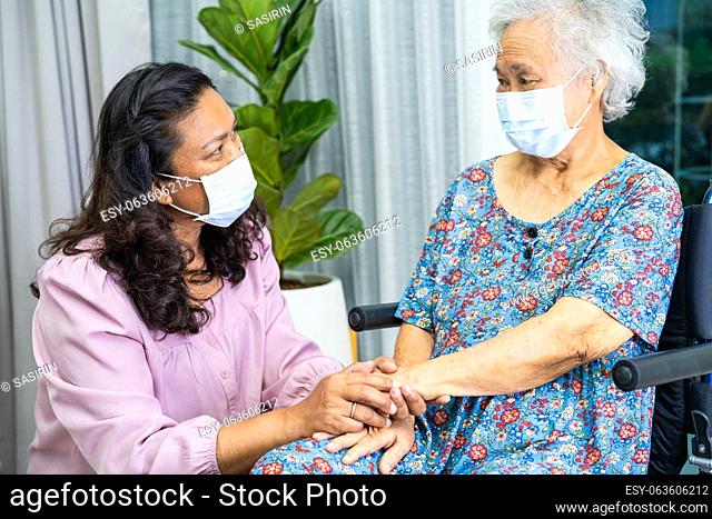 Caregiver help Asian senior woman on wheelchair and wearing a face mask for protect safety infection Covid19 Coronavirus