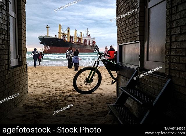 RUSSIA, KRASNODAR REGION - DECEMBER 2, 2023: People on a beach look at the Blue Shark dry cargo ship after it ran aground at the Black Sea resort of Anapa