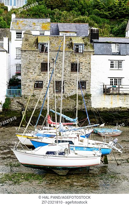 sailboats aground and old houses, Polperro, cityscape of the touristic village on southern coast of Cornwall with low tide in the river harbour and sailboats...