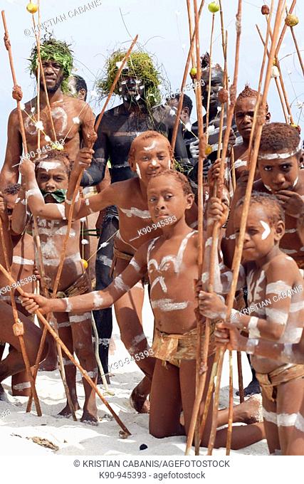 Melanesian men and children with the traditional Snake Dance body paint and clad on the skin and with traditional weapons and headdresses at the beach of Ra...