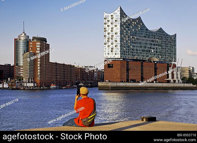 A man takes pictures of the Elbe Philharmonic Hall and Columbus House, Hafencity, Hamburg, Germany, Europe