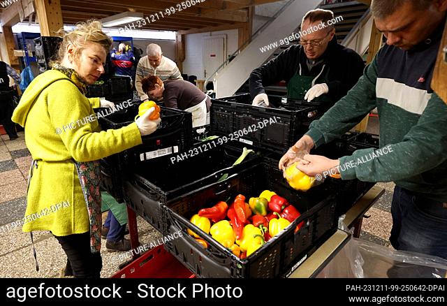PRODUCTION - 07 December 2023, Mecklenburg-Western Pomerania, Rostock: At the food bank in Rostock, food is checked, sorted and reloaded into boxes to be...