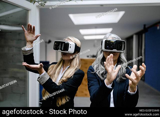 Mature and young businesswoman wearing VR glasses