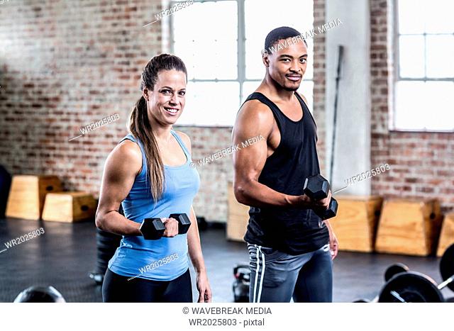 Fit couple doing dumbbell exercises