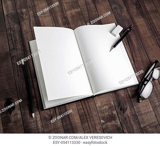Photo of blank book and stationery on wooden background. Template for placing your design