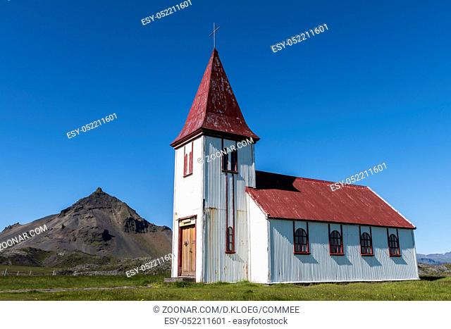 White church, Hellnakirkja, with red roof near the blue ocean at Hellnar on Iceland
