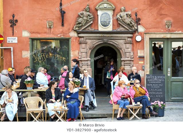 People having a rest in a cafe at Stortorget square in Gamla Stan, the ""old town"" of Stockholm, Sweden