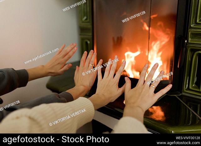 Man and woman warming hands in front of fireplace at home