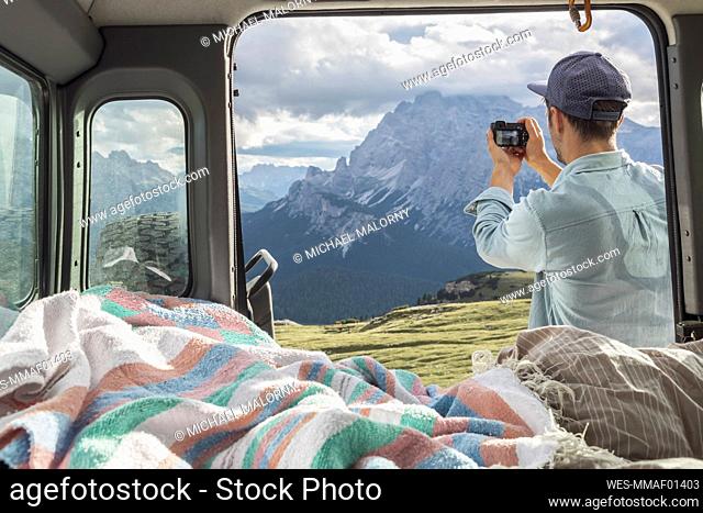 Man photographing scenic mountain ranges while standing by campervan. Sesto Dolomites, Dolomites, Alto Adige, Italy