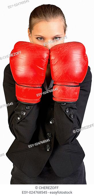 Businesswoman wearing boxing gloves standing in boxing stance, looking at camera. Isolated over white background