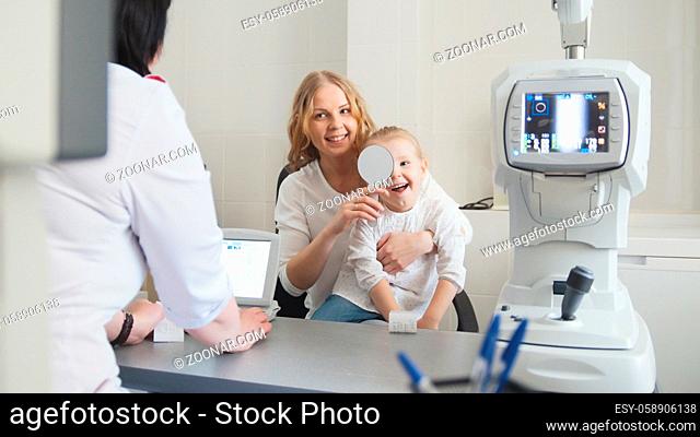 Medicine for children - optometrist in clinic checking little girl's vision, close up