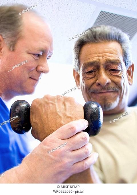 Physical Therapist assisting a man with weights