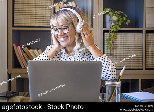Businesswoman listening music on headphones while working on laptop at home office. Caucasian young woman enjoying music on headphones