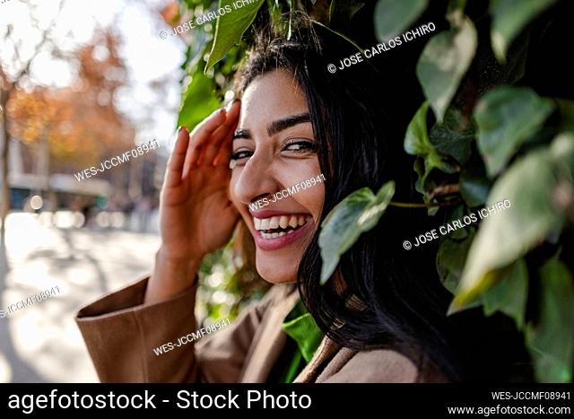Happy young woman standing in front of plants
