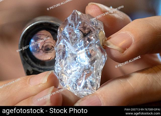 07 July 2020, Lower Saxony, Osnabrück: The face of geological preparator Angelika Leipner is reflected in a magnifying glass next to a rock crystal