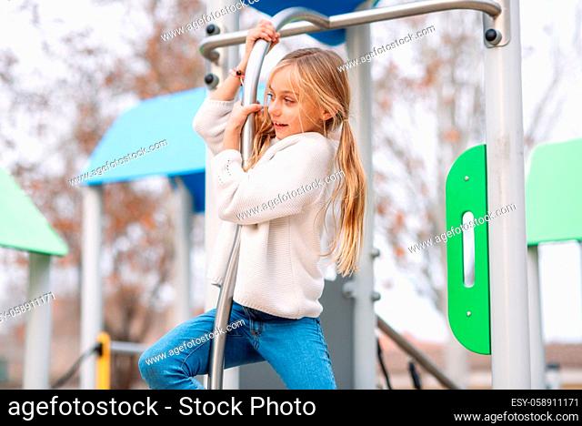 Pretty, little girl playing on children playground, ready to slide by pole