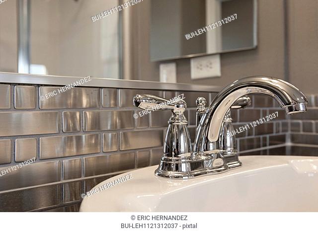 Faucet at sink and metallic backsplash in bathroom; Murrieta; California; USA