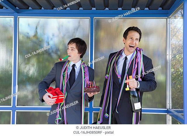 businessmen at bus stop, with party set