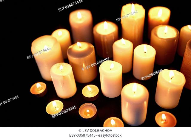 candles burning in darkness over black background