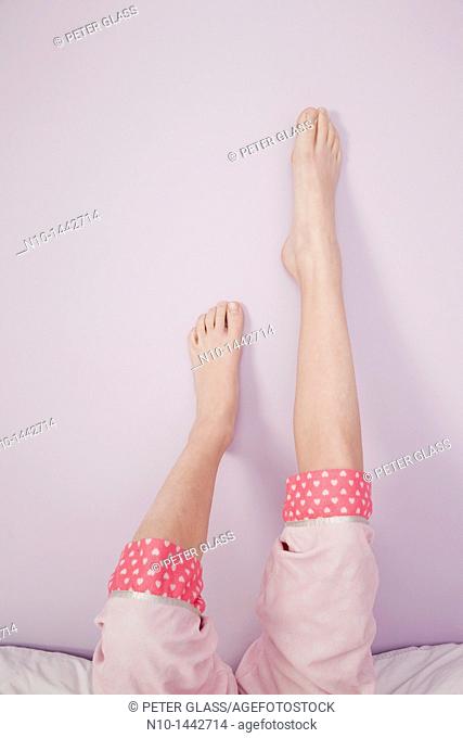 Preteen girl's legs and feet resting on a wall