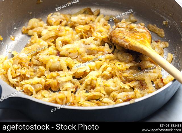 close up of fried onion with wooden spoon