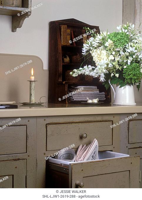 KITCHEN - Detail shot of recycle waste bin in cream color, distressed custom cabinets, early American styling, large bouquet of white cleome