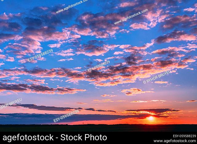 Sunset Sunrise Over Field Or Meadow. Bright Dramatic Sky And Dark Ground. Countryside Landscape Under Scenic Colorful Sky At Sunset Dawn Sunrise