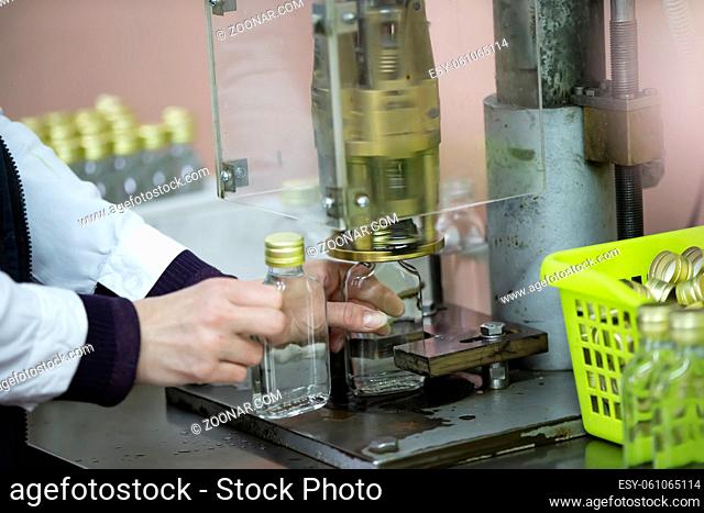 Worker hands and empty bottles on a conveyor belt in the production of alcoholic beverages