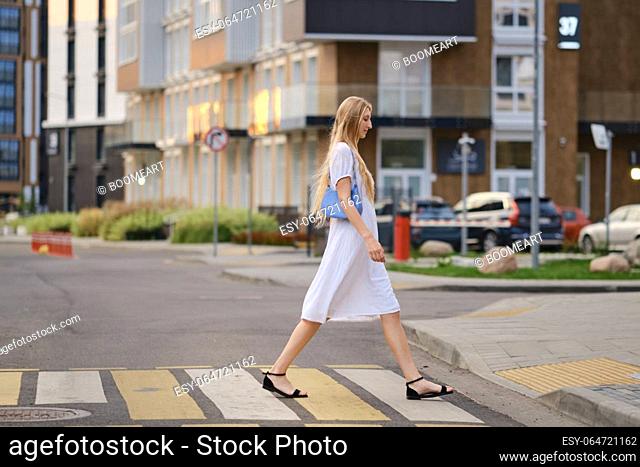 Tall woman crossing the road at a crosswalk