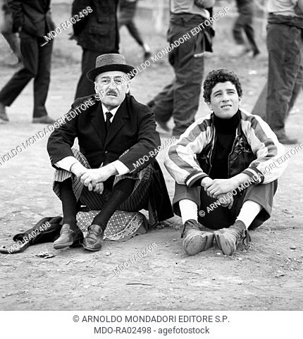Italian artist TotÃ² (Antonio De Curtis) and Italian actor Ninetto Davoli (Giovanni Davoli) sitting on the ground and looking far in the film The Hawks and the...