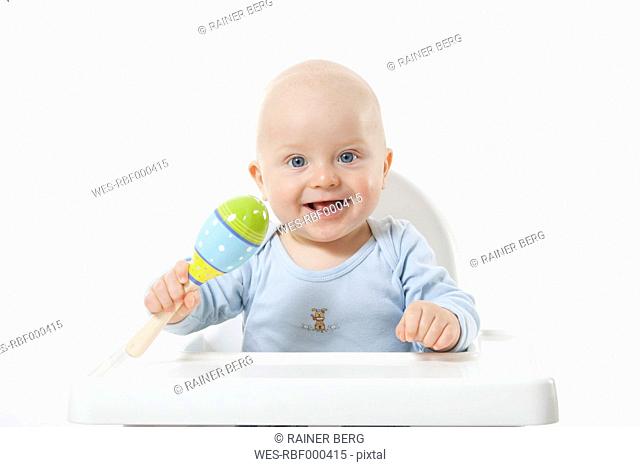 Baby boy 6-11 Months holding rattle, smiling