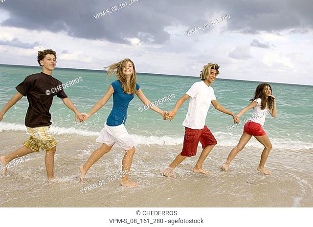 Two teenage boys and two teenage girls walking on the beach