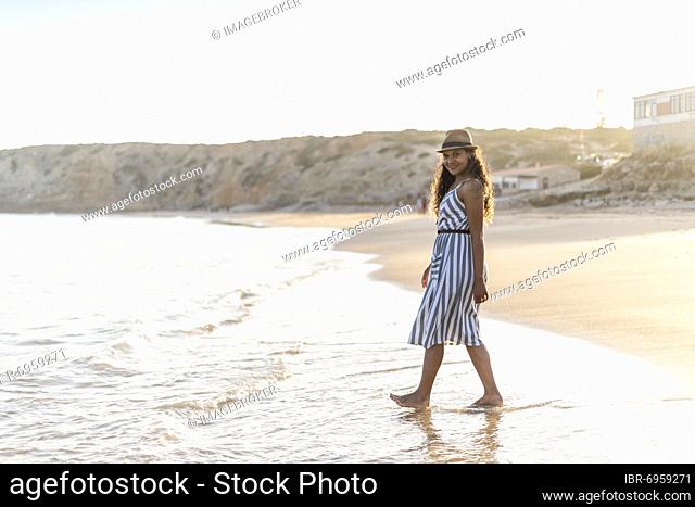 Portrait of a beautiful young woman on the beach by sunset in Algarve, Portugal, Europe