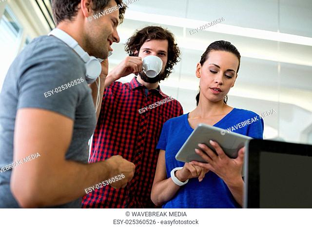 Team of graphic designers discussing over digital tablet
