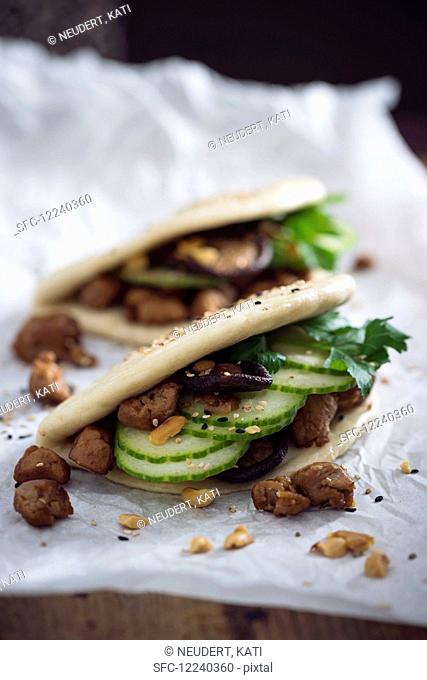Vegan bao tacos with soya strips, cucumber, shiitake mushrooms, roasted peanuts and sesame seeds