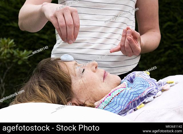 Reiki therapist with a client in a therapy session touching meridian points on the body