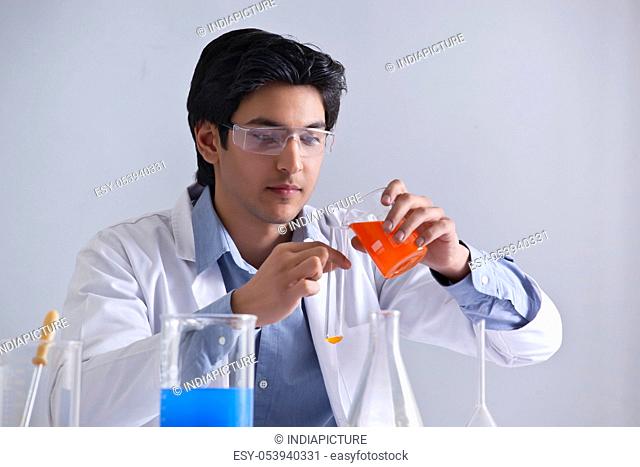 Young scientist pouring liquid in a test tube