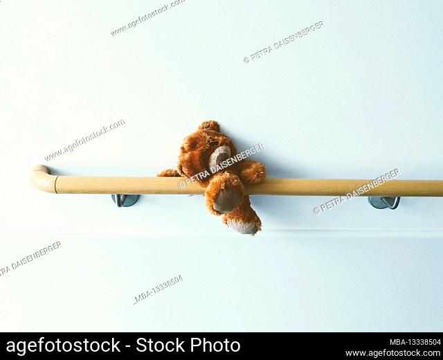 A forgotten, lone, lonely teddy bear is trapped on an armrest in the hospital
