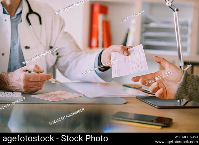 Doctor giving prescription to patient at doctor's office