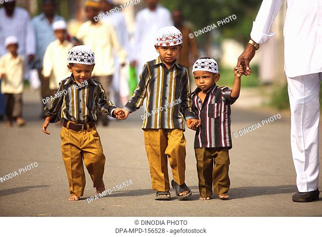Three brothers wearing same clothes accompanied by father arrive at Lashkar e Eidgaah grounds for their Eid al Fitr or Ramzan id namaaz ; Malegaon ; Maharashtra...