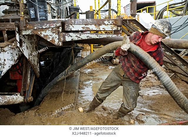 Mancelona, Michigan - A worker struggles with a hose while dismantling a natural gas drilling rig in the Antrim Shale field of northern Michigan