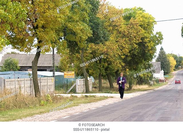 Woman walking along the road, Rawa Mazowiecka, Central Poland