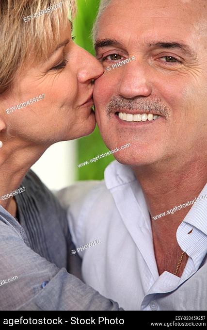 Mature woman kissing a smiling man on the cheek