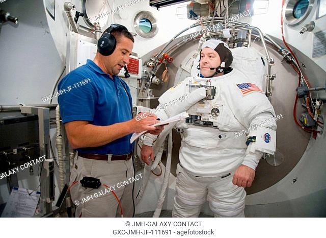 Astronaut Nicholas Patrick, STS-130 mission specialist, participates in an Extravehicular Mobility Unit (EMU) spacesuit fit check in the Space Station Airlock...