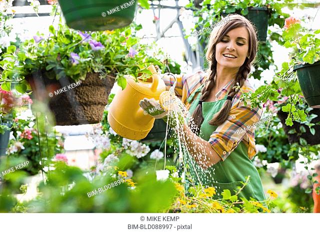 Caucasian woman watering plants in nursery